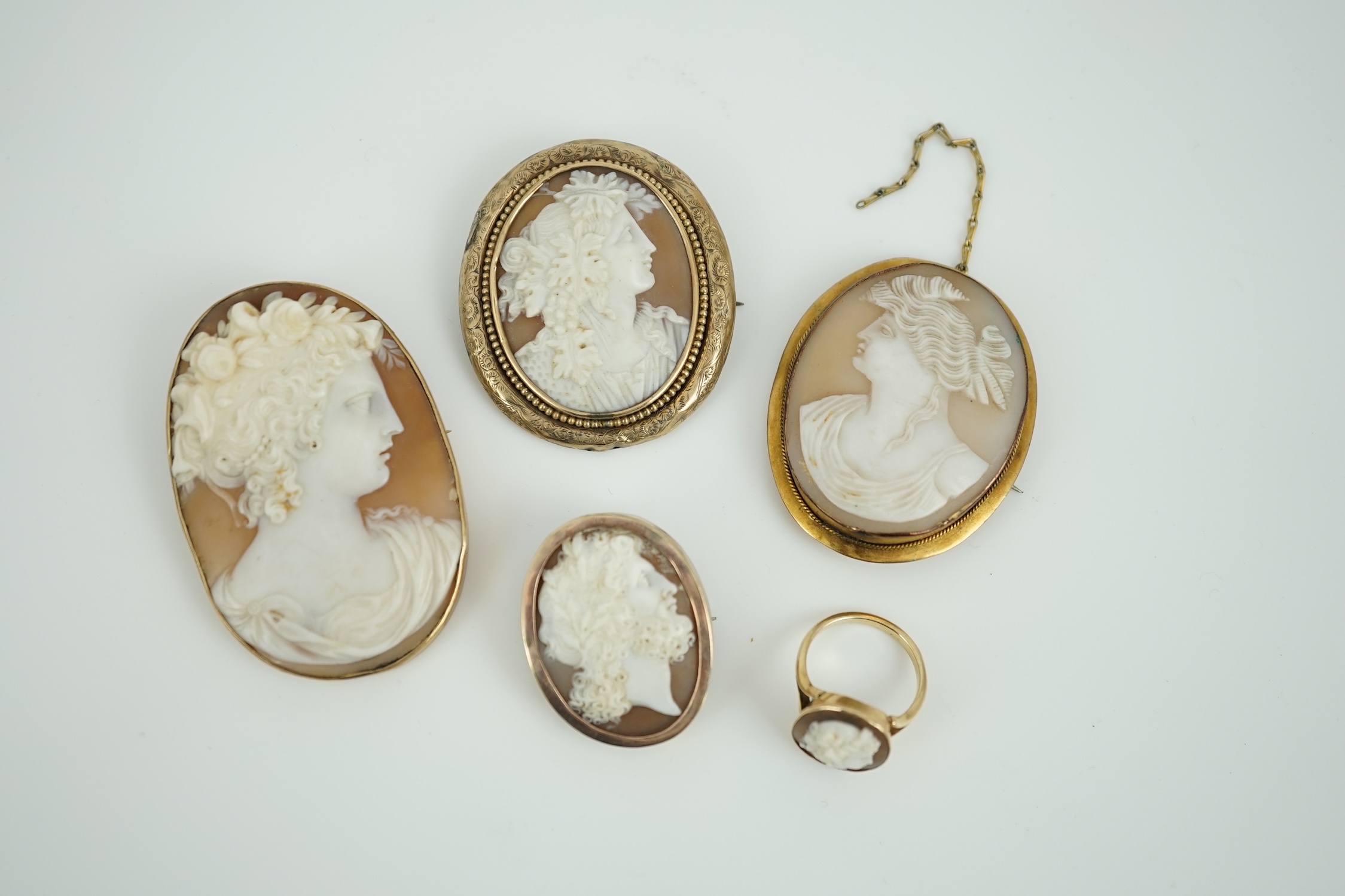 Four assorted early 20th century yellow metal mounted oval cameo shell brooches, largest 60mm, one stamped 9ct and a yellow metal mounted oval cameo shell ring.